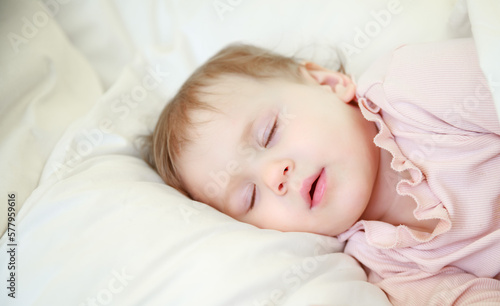 Little cute girl sleeps in her crib. The child is resting. Baby 1 year sleeps on a pillow. Healthy sleep in babies.