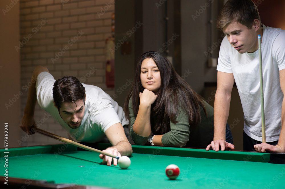 Fototapeta premium Young friends playing pool at bar