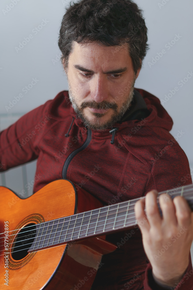 Obraz premium man with beard playing Spanish guitar looking at the strings
