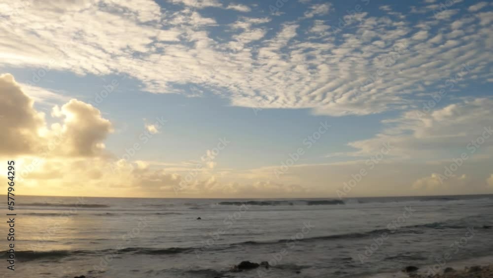 horizontal view of sunset at black rock of north east Cook Islands look out to the pacific ocean with golden clouds and reflection from the clam ocean water in lagoon and sunshine through clouds horizontal view of sunset at black rock of north east Cook Islands look out to the pacific ocean with golden clouds and reflection from the clam ocean water in lagoon and sunshine through clouds