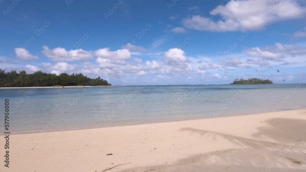 horizontal view right to left of look out from Muri Beach Cook Islands to Koromiri and Taakoka islets within lagoon with calm sea turquoise blue water during day sunshine cloud cast on sandy beach 