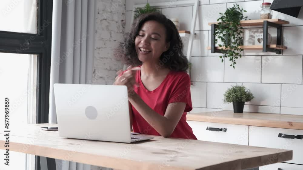 Curly-haired African American woman folding hands chatting online with a friend at home. Happy young female sitting at a desk in front of your laptop and has video call Curly-haired African American woman folding hands chatting online with a friend at home. Happy young female sitting at a desk in front of your laptop and has video call