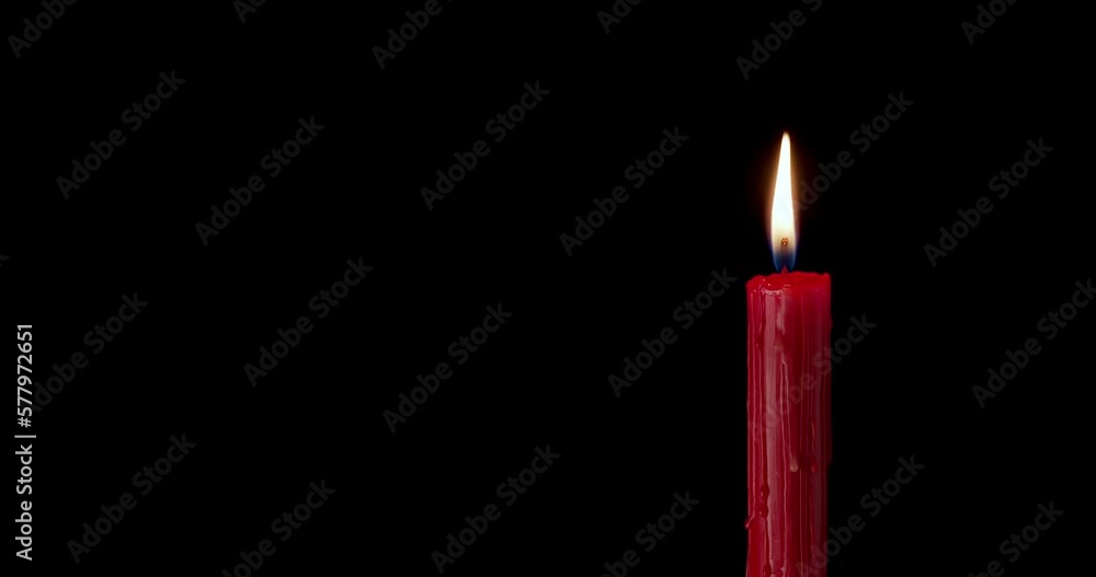 A single red candle burning. Isolated candle burning with dark background. Red paraffin candle with yellow shades burns on a black background. slow motion A single red candle burning. Isolated candle burning with dark background. Red paraffin candle with yellow shades burns on a black background. slow motion