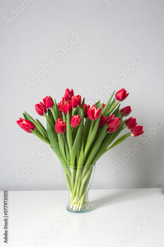 Red kung fu tulips stand in a glass vase on the table. Bouquet of flowers