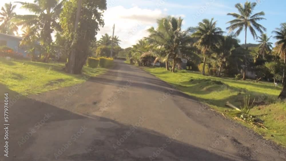 moving forward riding view at a backroad in tropical Pacific Islands where Polynesian culture inhabitants with flourish vegetation and coconut trees and mountain along pave road in a neighborhood moving forward riding view at a backroad in tropical Pacific Islands where Polynesian culture inhabitants with flourish vegetation and coconut trees and mountain along pave road in a neighborhood