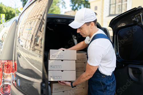 The courier in the uniform is a professional man, the delivery of the box is ordered by the customer at home.
