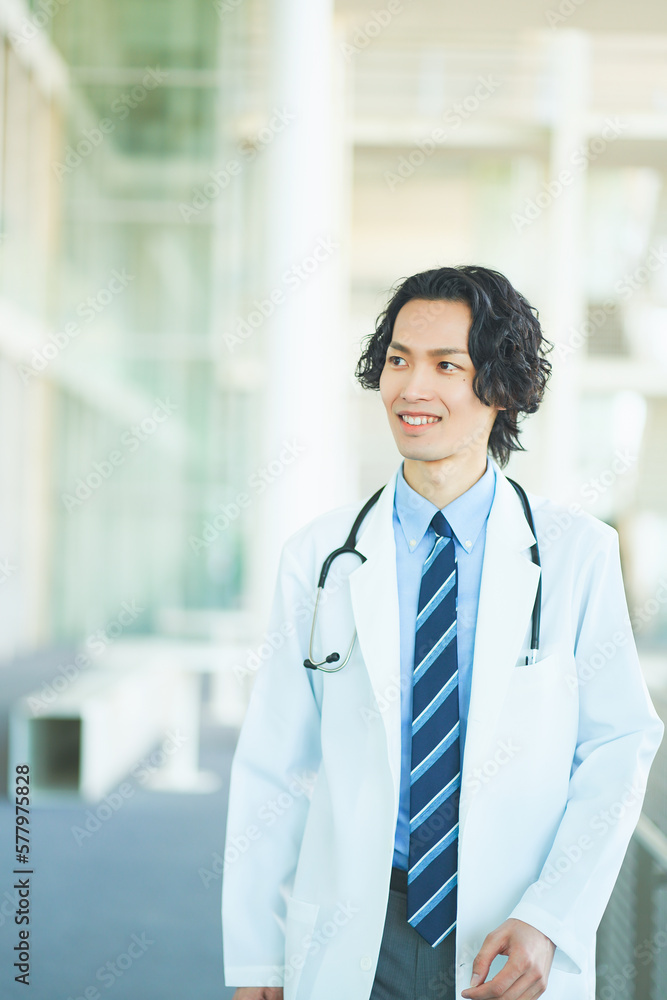 総合病院の廊下を歩く若い男性医師 総合病院の廊下を歩く若い男性医師