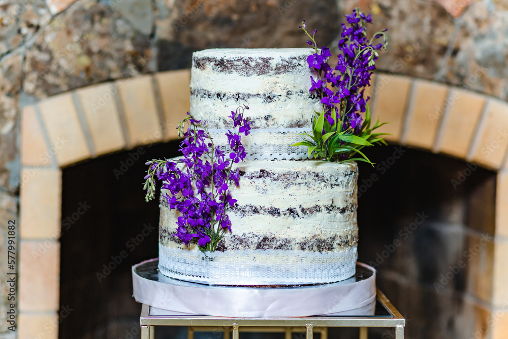 Close up of birthday cake decorated with lavender flower in banquet hall in front of the fireplace