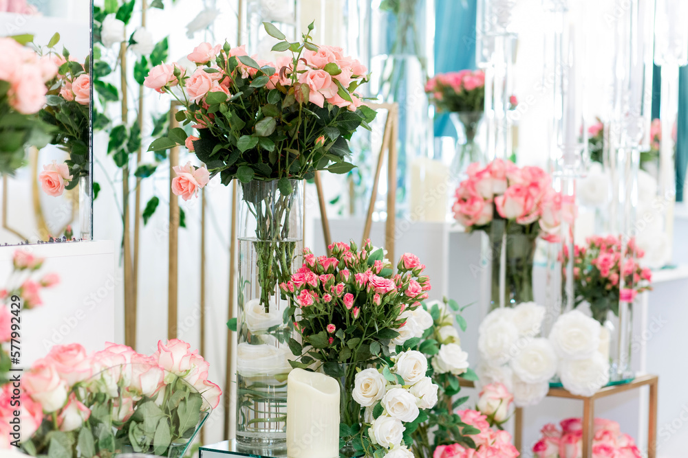 Gorgeous wedding decoration in restaurant with natural roses in glasses filled with water and designed with candles