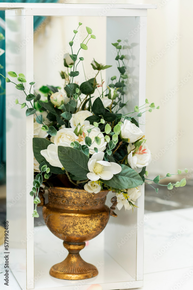 Closeup of wedding ornament. Artificial white flowers in metal vase on the floor in banquet hall