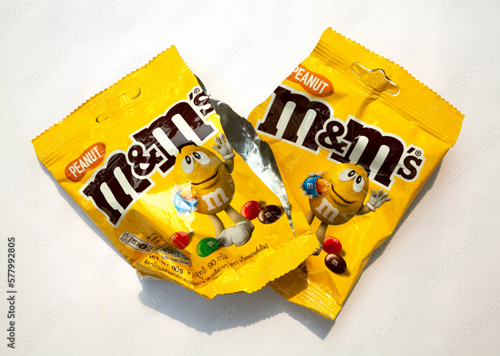 2 m&m's peanut chocolate candy empty crumpled wrappers isolated on white.  Popular candy packaging with a brand logo discarded as garbage Stock Photo