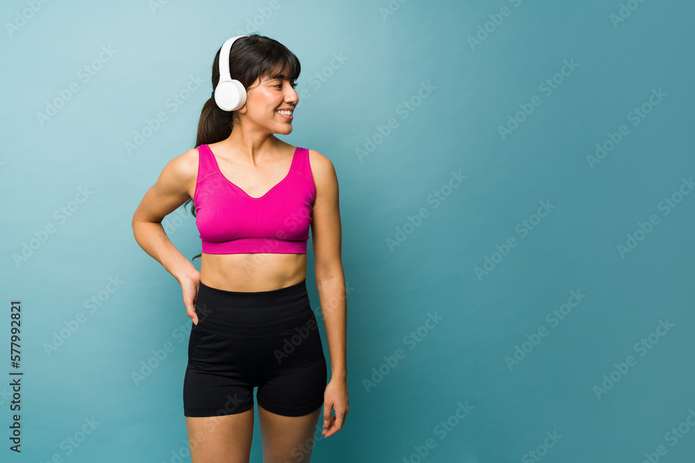 Fitness young woman with headphones showing her arm muscles