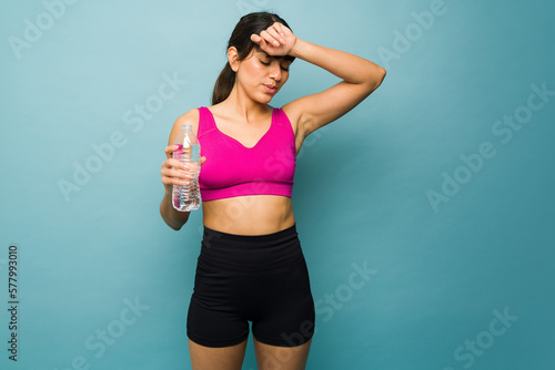 Tired active woman drinking water after working out