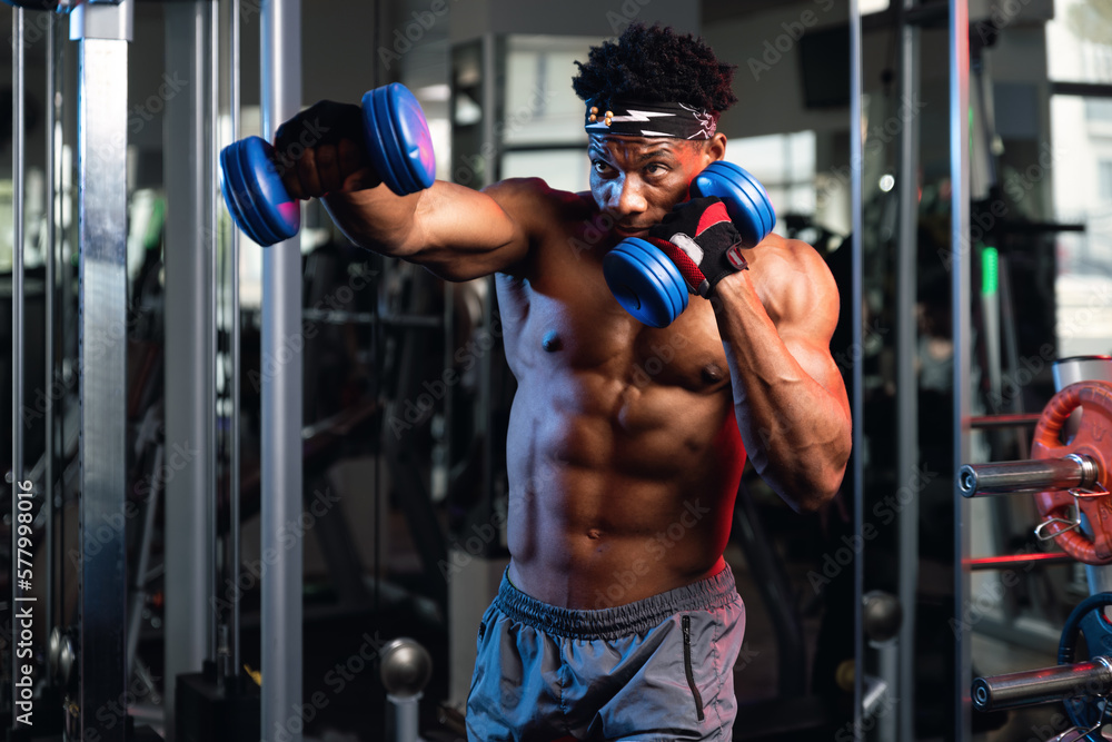 Portrait of a 20s black muscular male fist working out with dumbbells Portrait of a 20s black muscular male fist working out with dumbbells