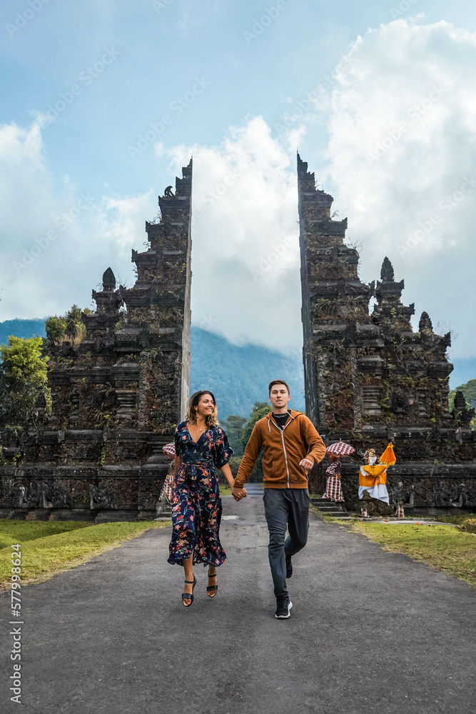 Obraz premium Young Couple Running Through Handara Gate In Bali, Indonesia