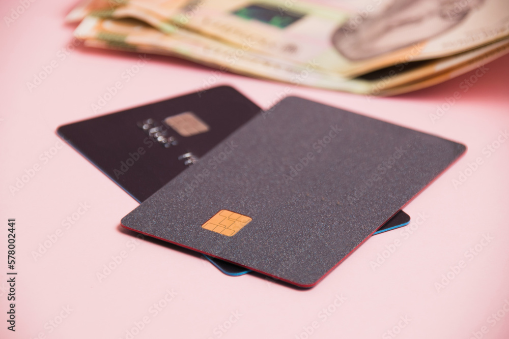 Bank cards with modern chips and money on a pink background. Concept of safe online operations with bank accounts and protection of bank cards from fraudsters Bank cards with modern chips and money on a pink background. Concept of safe online operations with bank accounts and protection of bank cards from fraudsters
