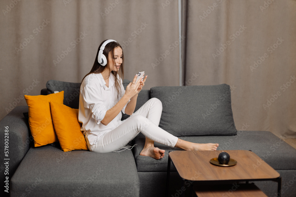 Happy and smiling caucasian female in earphones use cellphone have webcam digital online communication at home. Happy and smiling caucasian female in earphones use cellphone have webcam digital online communication at home.