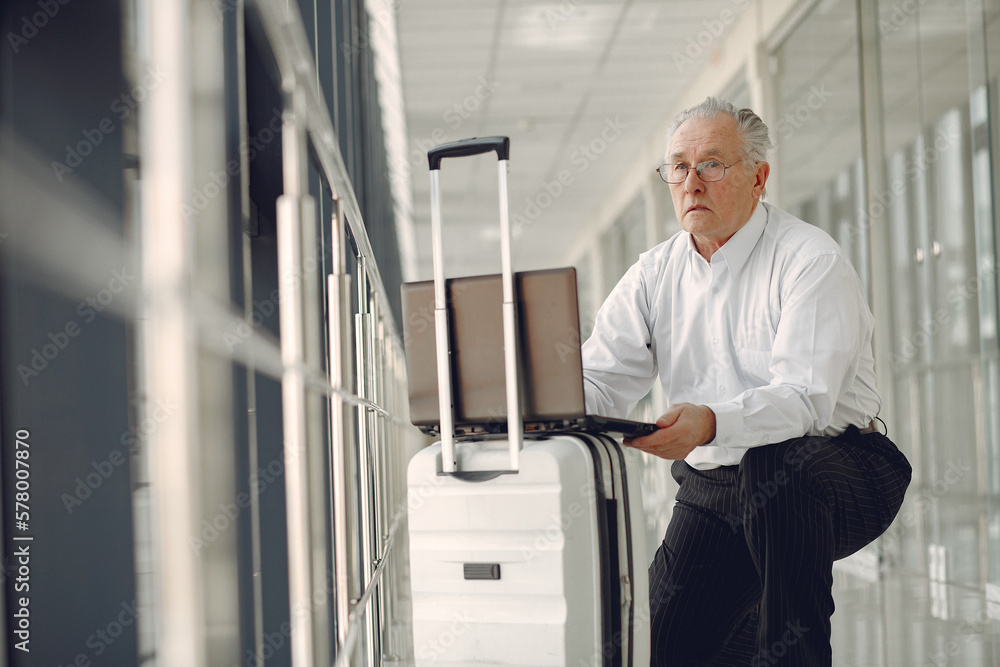 Elegant old man at the airport with a suitcase