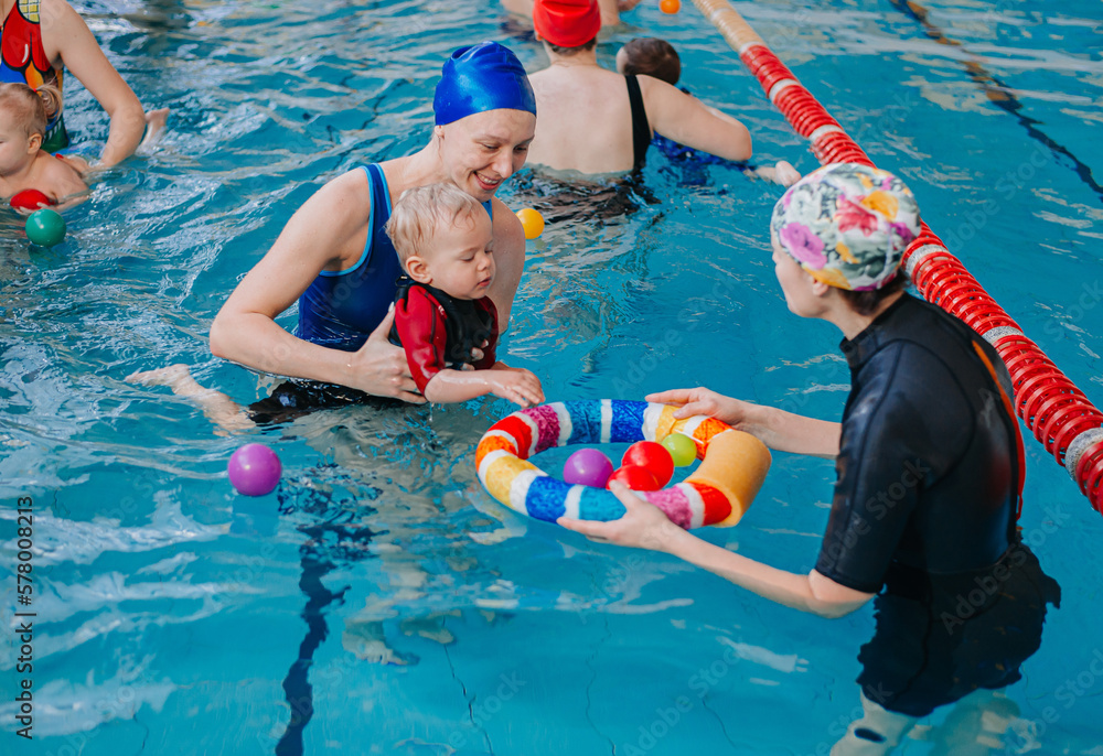 A swimming teacher teaches a kid to swim in the pool