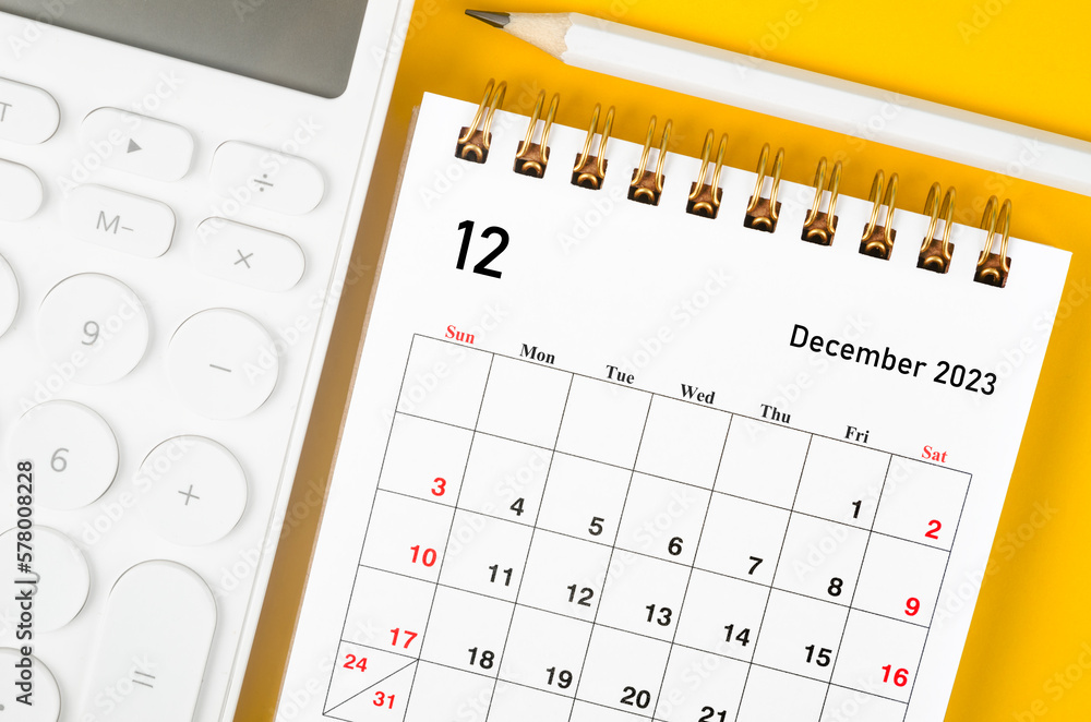 The December 2023 Monthly desk calendar for 2023 year and calculator with pen on yellow background. The December 2023 Monthly desk calendar for 2023 year and calculator with pen on yellow background.