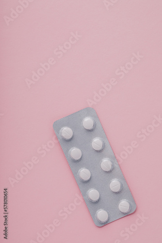 Pills in blister pack on pink background, top view