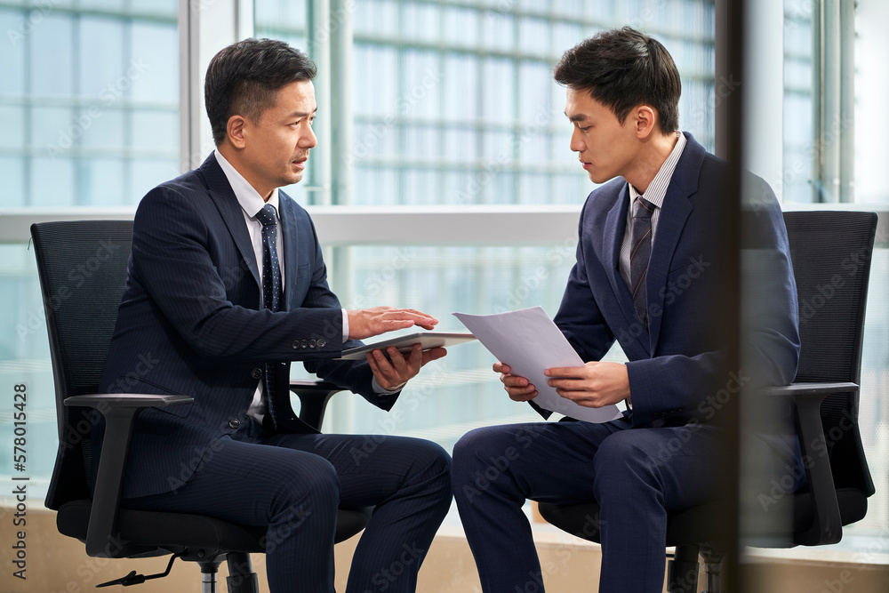 two asian corporate executives discussing business in office two asian corporate executives discussing business in office