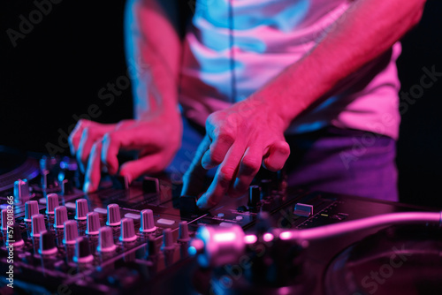 DJ playing music on party in night club. Close up photo of professional disc jockey mixing vinyl records with sound mixer device