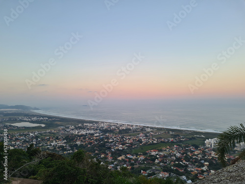 Beautiful and colorful sunset from a hill overlooking the city and the ocean with waves on the background © Giulia
