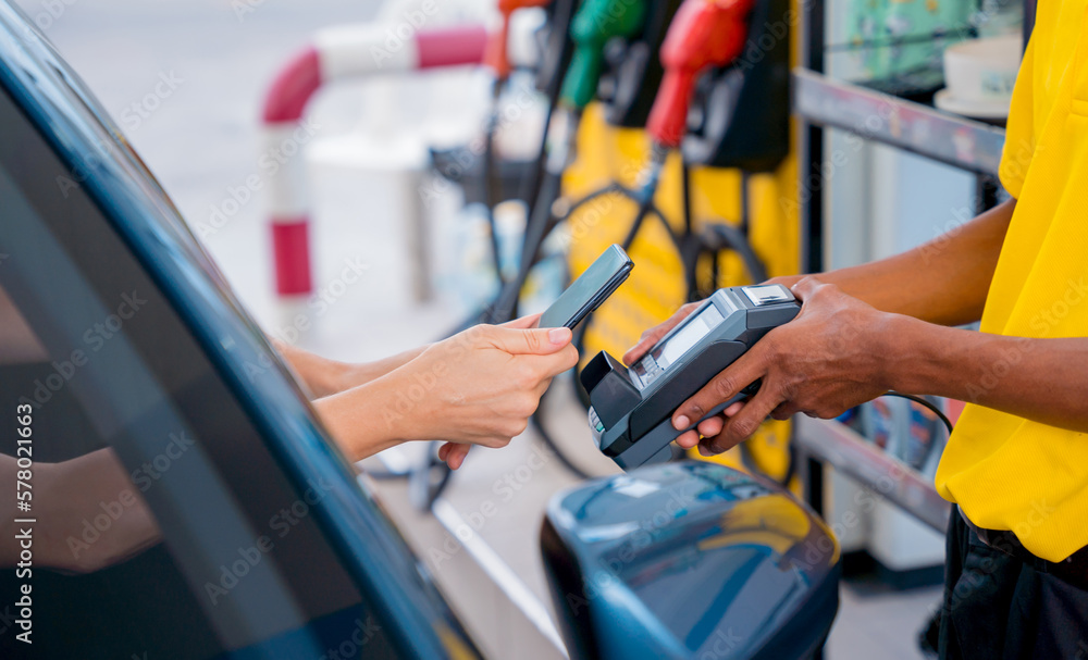Woman using contactless payment by mobile phone with QR code at car filling station Woman using contactless payment by mobile phone with QR code at car filling station