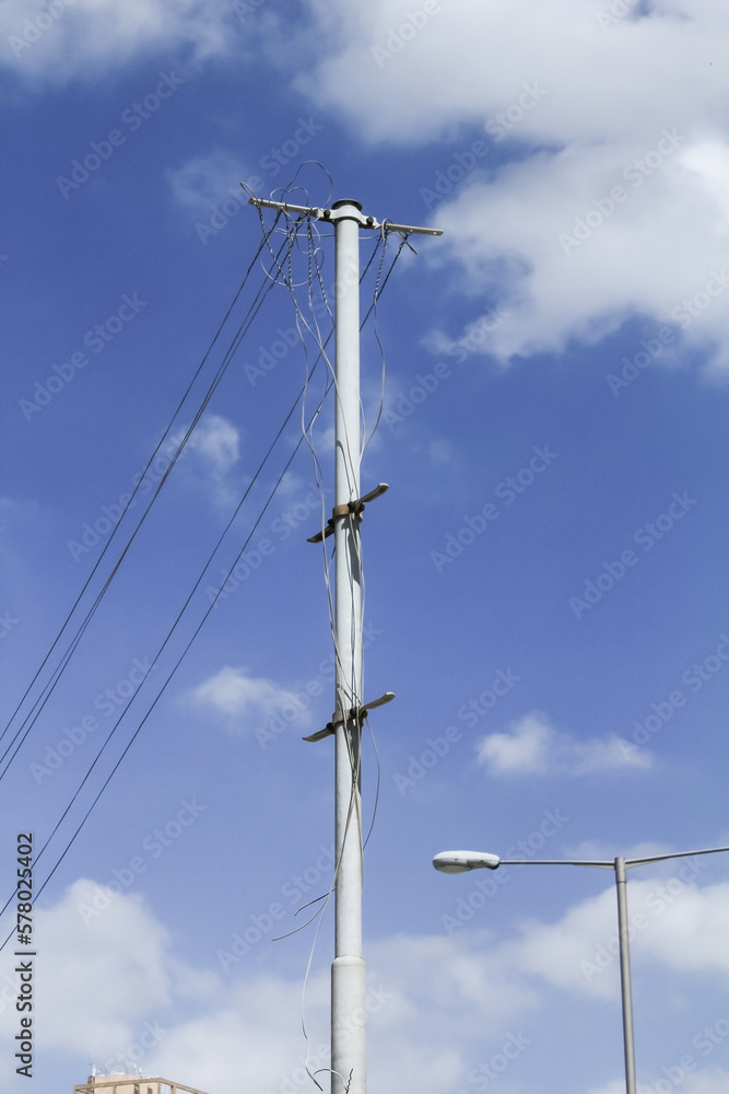 Bottom view of utility poles with blue sky. Blue sky and white clouds. Illustration on the theme of electricity supply. Rural electrification.