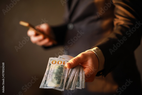 Business Man Displaying a Spread of Cash over a gray vintage background