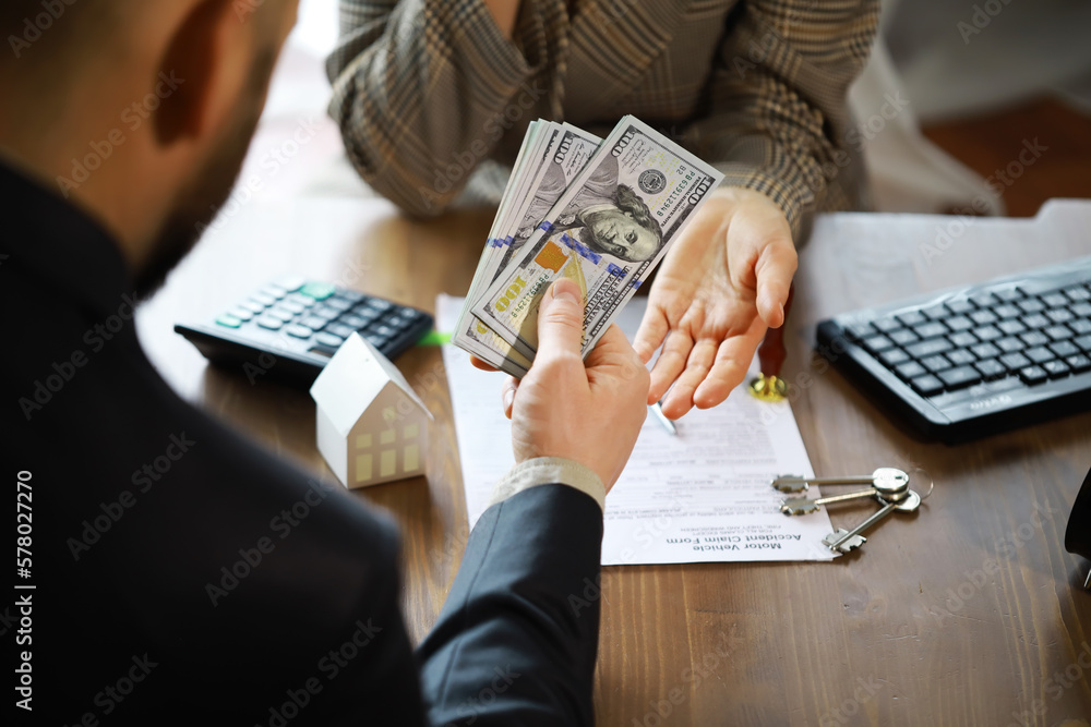European businesswoman working in real estate company. She is giving cash money to male customer. - obrazy, fototapety, plakaty 