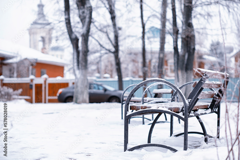 park bench on a winter alley at snowfall. bench with snow after snowstorm or in snow calamity in europe park bench on a winter alley at snowfall. bench with snow after snowstorm or in snow calamity in europe