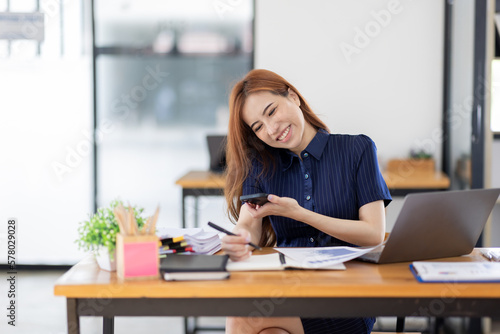 Business Asian woman Accounting using Phone calculating income-expenditure and analyzing real estate investment data report Financial and tax Business systems concept. © David