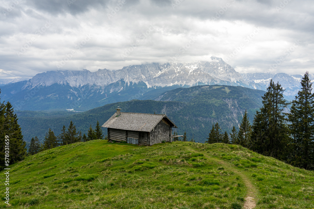 Hütte auf Almwiese in den Vergen mit Pfad oder Weg und Bergpanorama.