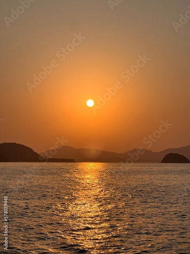 Sunset with reflection in the sea. Red sunset in the mountains in the sea. Fishing schooners laid up on the shore of the island. Mountains in the distance of the sea. Reflection of the sea in the sand