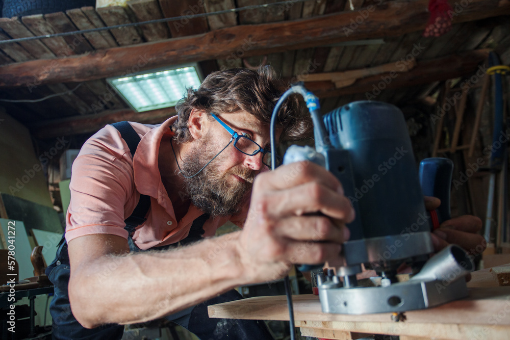 Carpenter using working tools while working on a wood in carpentry workshop Carpenter using working tools while working on a wood in carpentry workshop