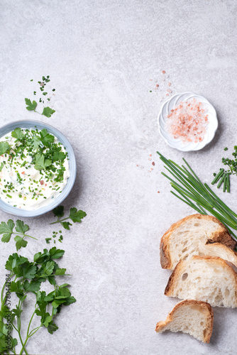 Ingredients for simple green butter board. Butter with fresh herbs: wild onion, parsley, rosemary and pink salt on a wooden board, gray stone background, rustic style. Simple and healthy snacks