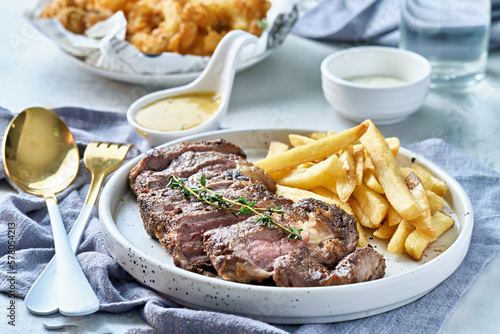 tasty grilled beef steak with rosemary garnish and french fries