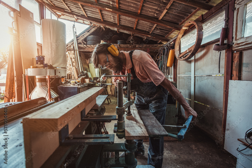 Carpenter using working tools while working on a wood in carpentry workshop Carpenter using working tools while working on a wood in carpentry workshop