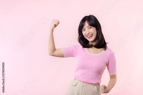 Portrait young asian woman proud and confident showing strong muscle strength arms flexed posing  feels about her success achievement. Women empowerment  equality  healthy strength and courage concept