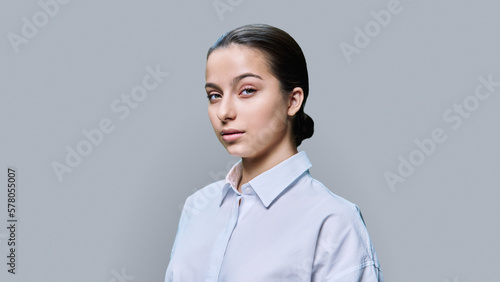 Portrait of young pretty teenage female posing against gray studio background