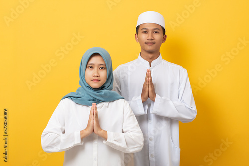 Young asian muslim man and woman celebration Ramadan and Eid Al-Fitr doing forgive gesture Halal Bihalal (Mohon Maaf Lahir dan Batin) give forgiveness at the end of the fasting period photo