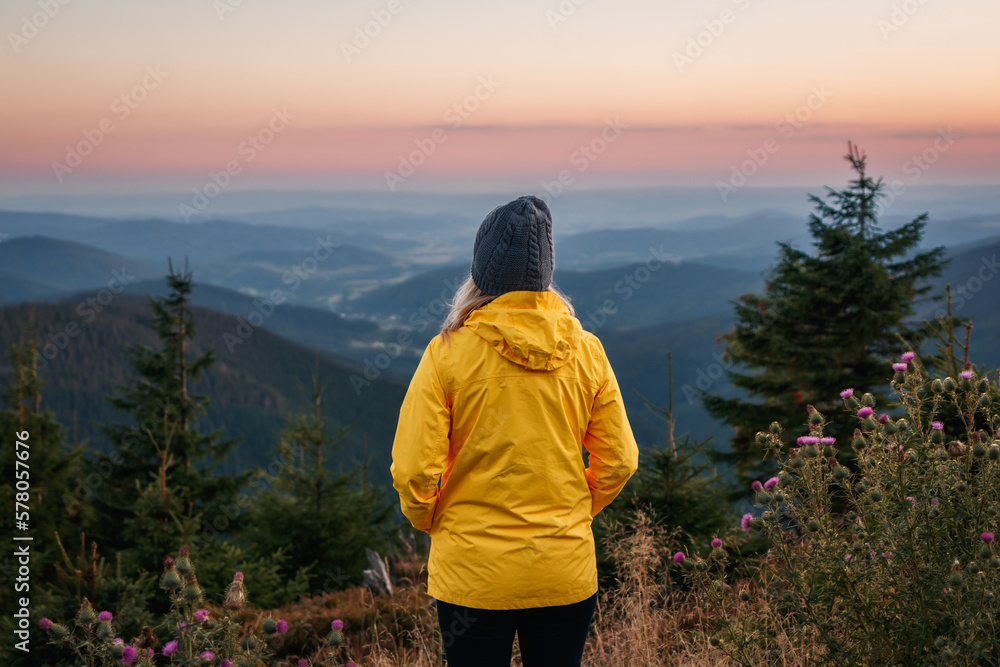 Woman looking at mountain range during sunset. Hiking in mountains Woman looking at mountain range during sunset. Hiking in mountains