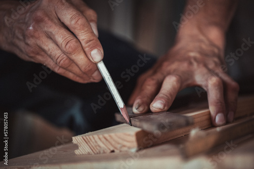 Fototapeta Carpenter using working tools while working on a wood in carpentry workshop