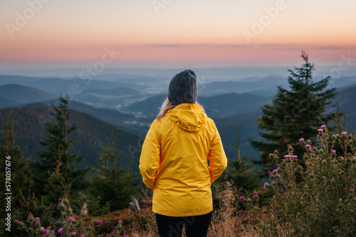 Woman looking at mountain range during sunset. Hiking in mountains