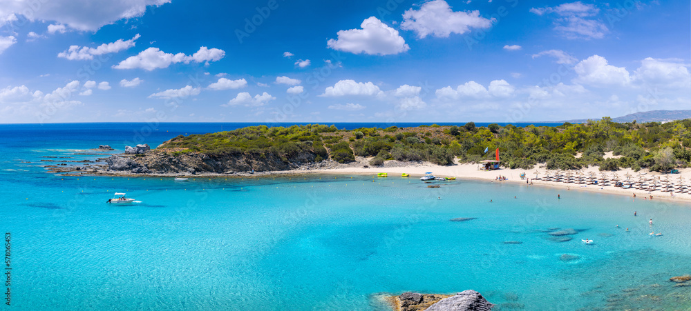 Crystal clear turquoise water in a Glystra beach. Cane umbrellas and sunbeds on an beach resort - vacation concept on Greece islands in Aegean and Mediterranean sea. Near Lindos at east Rhodes. Greece