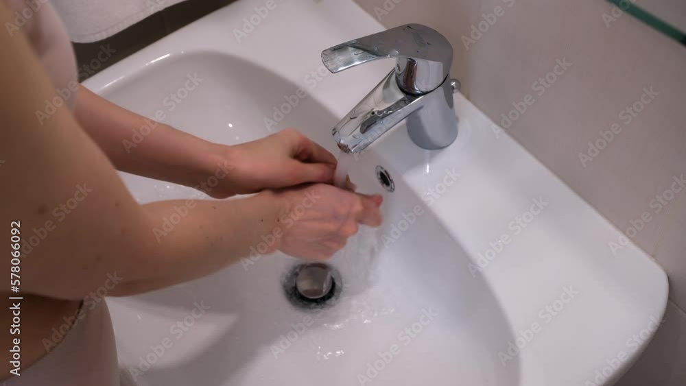 Woman is washing her hands with soap in sink in bathroom, hands closeup. Self personal hygiene concept. Useful healthy habit, everyday routine. Woman is washing her hands with soap in sink in bathroom, hands closeup. Self personal hygiene concept. Useful healthy habit, everyday routine.