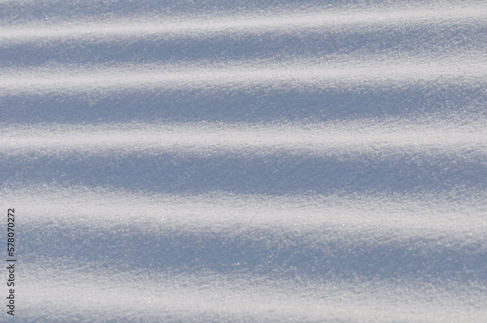 Obraz premium Snow lies in waves in a cold snowy winter, the play of light in straight lines