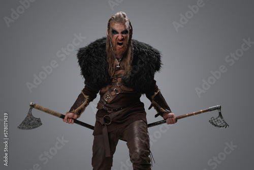 Studio shot of furious ancient viking with painted face and black fur.